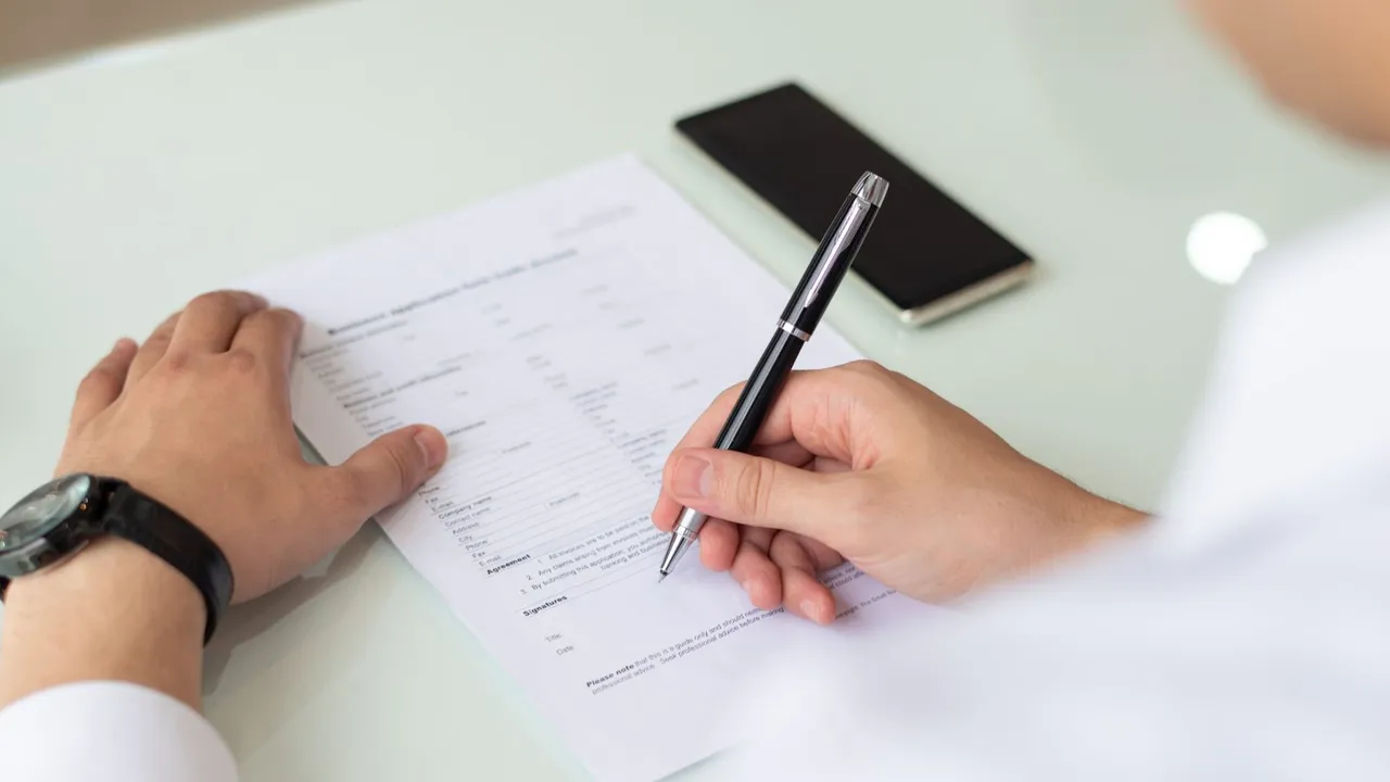 Mãos preenchendo um formulário de inscrição sobre uma mesa
