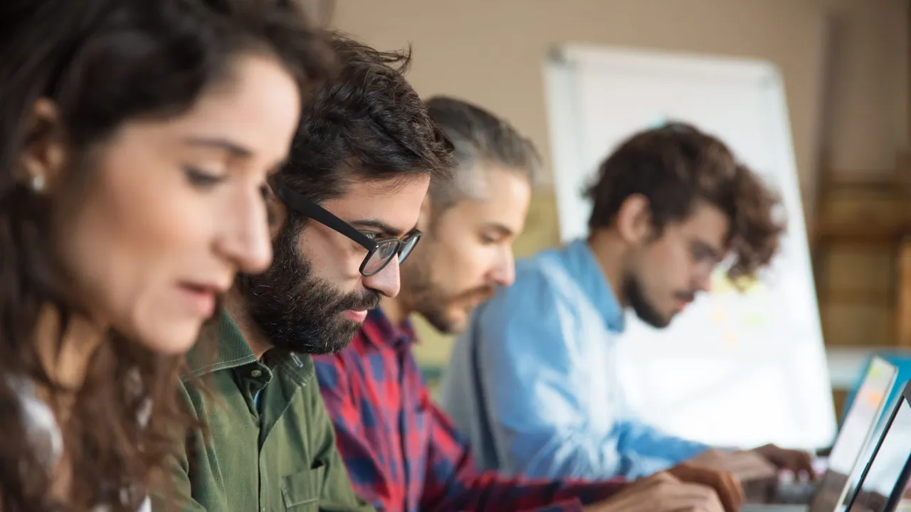 Alunos lado a lado usando notebooks em uma sala de treinamento