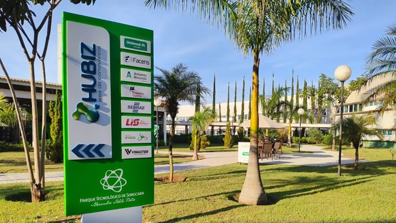 Placa verde da Hubiz diante dos jardins e prédios do Parque Tecnológico de Sorocaba