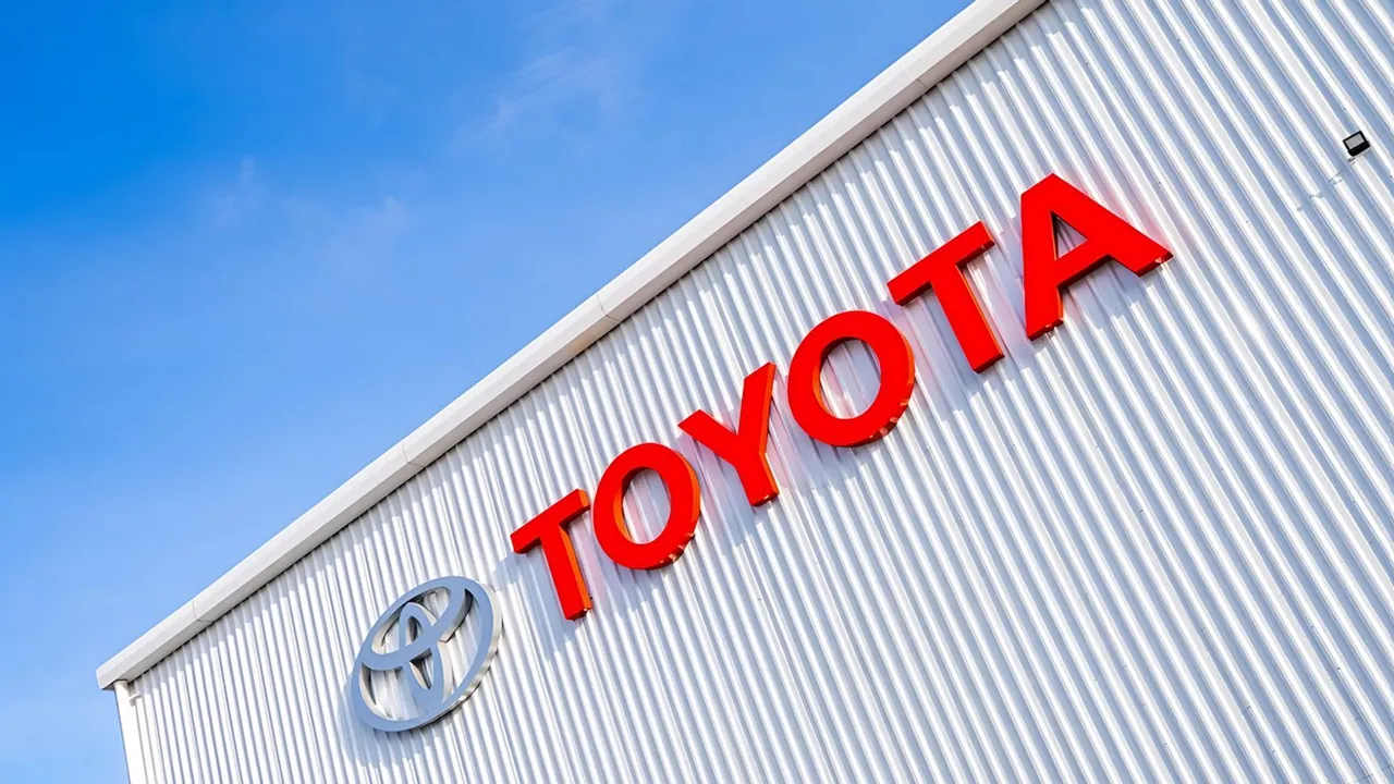 Letreiro vermelho da Toyota na fachada metálica de um prédio, sob céu azul